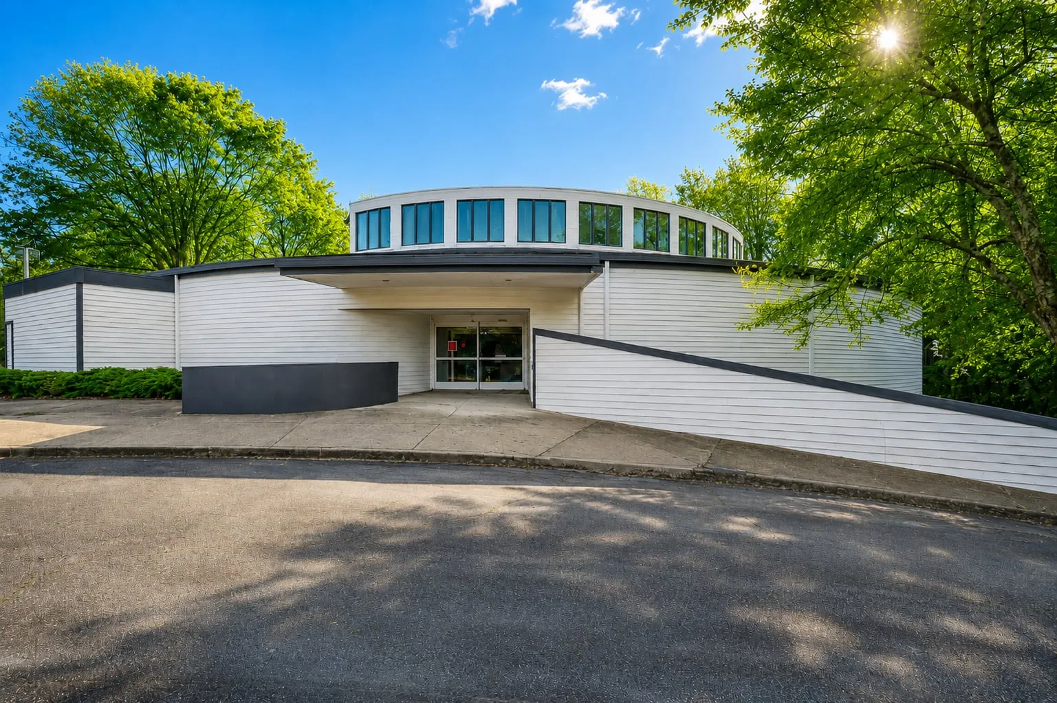 Front exterior of 125 Dillon Drive, Spartanburg SC — single-story former medical office with curved façade, clerestory windows, covered entry, and accessibility ramp